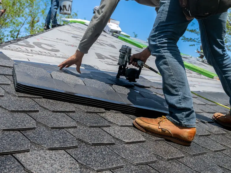Roofer installing shingles on a house